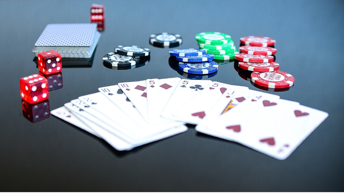 A picture of fanned out cards withpoker chips and dice behind them
